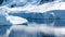 Tiny Penguins on Ice Floe and on Huge Iceberg with Fissure in Antarctica near Petermann Island