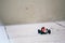 Tiny red toy car with number five plate on an outdoor brick rough floor