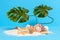 Tiny sandy treasure island with message bottle, seashells, starfish and monstera