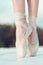 On the tips of the toes. Female feet in pointe shoes. Pointe shoes worn by ballet dancer. Ballerina shoes. Legs in white