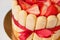 tiramisu cake close up with strawberries, ladyfingers, mascarpone and red bow-tape on white