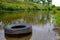 A tire from a car in the river pollutes the environment