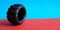 Tire on a red-blue double background. Close up toy black thick tyre with pattern. Side view. Place for copy space. Horizontal