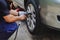 Tire Replacement concept. Mechanic Using Electric Screwdriver Wrench for Wheel Nuts in Garage.