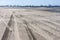 Tire tracks on the beach and Rotterdam industry in background