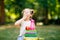 Tired adorable little kid girl reading book and holding different colorful books, apples and pencils on first day to