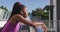 Tired african american woman wearing earphones taking a break from running on the city bridge