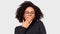 Tired African American young woman yawning, wearing black blouse and round eyewear, posing over white studio wall. Sleepy Afro