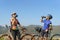 Tired Asian cyclist couple taking a break to drink water from a bottle with a beautiful lake and mountains in the background