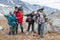 Tired backpackers with heavy backpacks standing in mountains, four mountaineers portrait with different ages