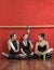 Tired Ballet Dancers Sitting On Hardwood Floor