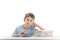 Tired boy doing homework at table and attentively reads book. Portrait of schoolboy at desk with stack of notebooks. White