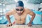 Tired, breathing and man swimming for fitness, training and race in a stadium pool. Strong, sports and face of an