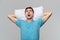 Tired brunet man in a blue tee resting on a white pillow  over grey background.