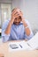 Tired businessman with paperwork at desk