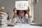 Tired, busy woman sitting at an office desk with paperwork and holding a HELP sign