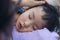 Tired Chinese kid sleeping on mom`s shoulder closeup portrait