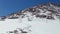 Tired climbers descend from a rocky mountain along snow-covered path. Winter day