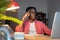 Tired confused African American man looking at laptop screen sits at office table with notepad