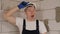 A tired construction worker in a white hard hat is standing in a new apartment.