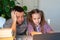 Tired dad helps daughter online lessons on laptop