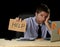 Tired desperate businessman in stress working at office computer desk holding sign asking for help