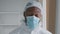 Tired doctor African American specialist surgeon medical worker takes off special uniforms sterile mask exhales from