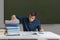 Tired and exhausted teacher is correcting many exams in classroom