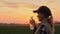 Tired farmer woman drinking clean water from bottle at sunset