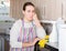 Tired female is standing after cleaning in the kitchen