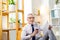 Tired grey-haired man relaxing in bright chair bag with coffee