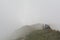 Tired hiker lies on a mountain ridge in a thick fog