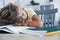 Tired kid sleeping with his head rested on a table with a book