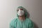 Tired male nurse, with plastic protective eyeglasses and respirator ffp2, cap, gown, with  personal protective equipment to