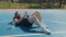 Tired man in sportswear after playing basketball game lying down on ball relaxing using smartphone