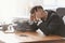 Tired mature businessman at table in office. Time management concept