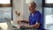 Tired mature male doctor sitting down at table, starting working typing on laptop computer.