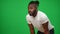 Tired motivated African American football player on green screen looking away wiping sweat off forehead. Portrait of