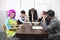 Tired multiethnic businesspeople with colleague in pink wig at meeting