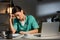 Tired nurse in uniform sitting at table and looking at clipboard during night shift