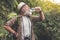 Tired old man drinking water from bottle in woodland