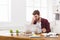 Tired, overworking businessman with laptop in modern white office