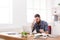 Tired, overworking businessman with laptop in modern white office