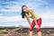 Tired runner girl taking a break breathing during jogging training workout outdoor on desert trail. Asian woman sweating