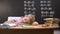 Tired schoolboy napping on desk, fallen asleep while preparing assignment