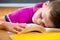 Tired schoolboy sleeping on book