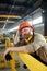 Tired or sick engineer in workwear and hardhat leaning by bar while having break