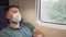 Tired sleeping train commuter wearing PPE face mask for safety. Concept travel during pandemic. Protective medical mask