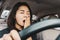 Tired sleepy Asian woman yawning during driving car