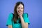 Tired sleepy woman yawns, covers her mouth with hand. Very boring, uninteresting. Violet studio background.